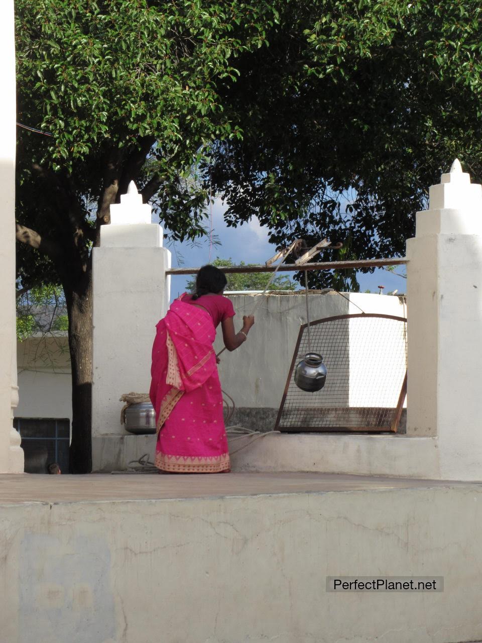 Mujer sacando agua del pozo